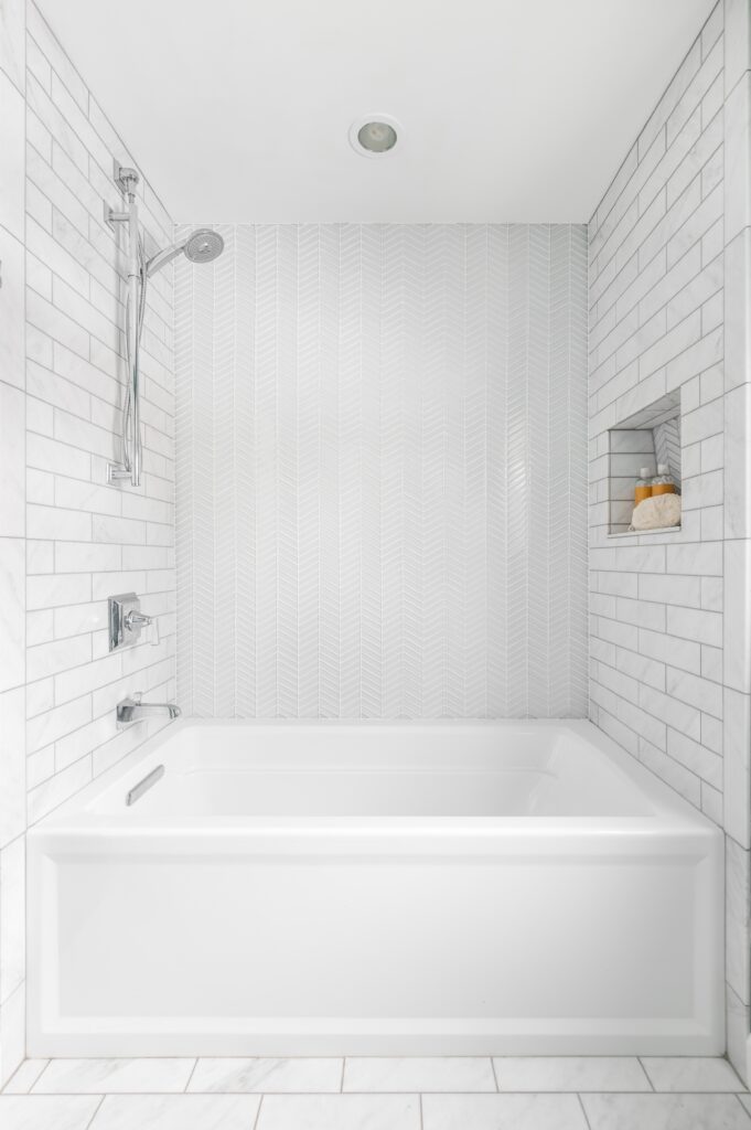 a gorgeous white tiled bathroom with a bath and shower